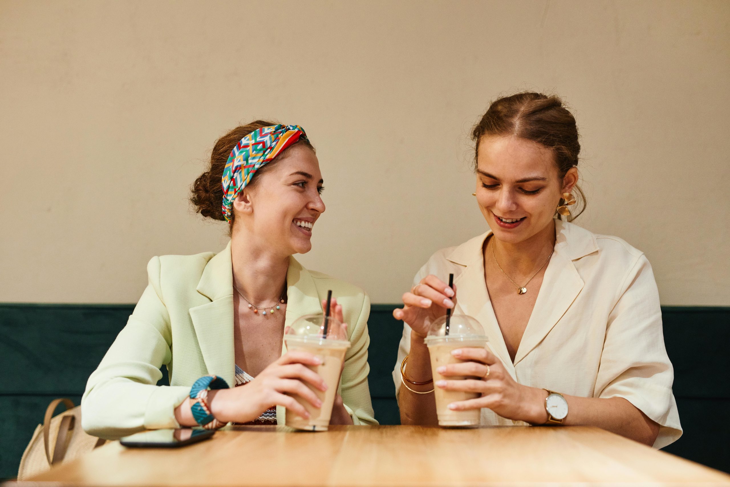 Two young women having a lively conversation over iced coffee at a café.